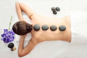 Stone treatment. Top view of a beautiful young woman lying face down with spa stones on her back. Beauty treatment concept.